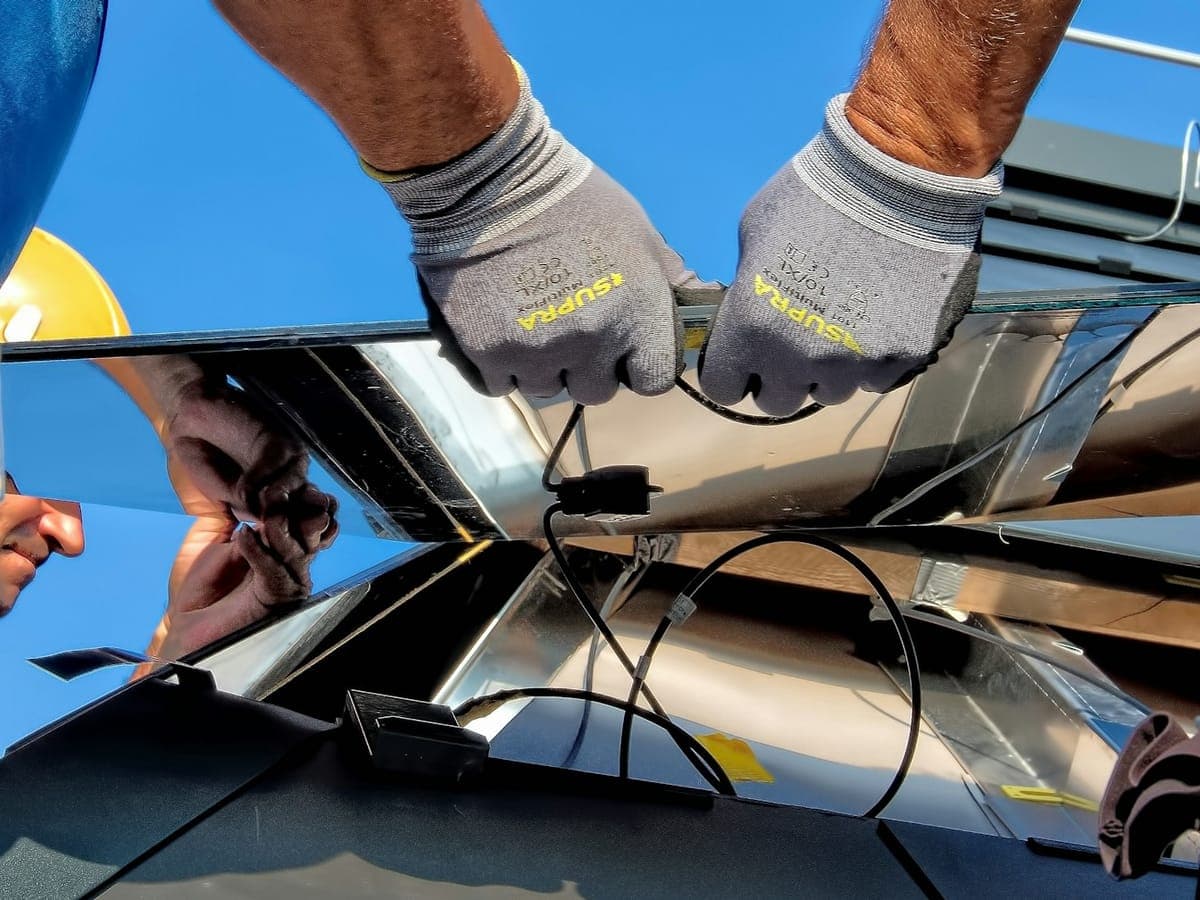 Mani di un tecnico che collegano i cavi di un pannello solare